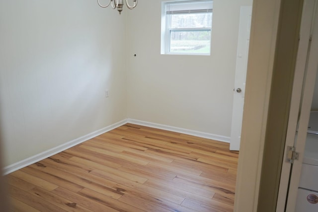 spare room with a chandelier and light wood-type flooring