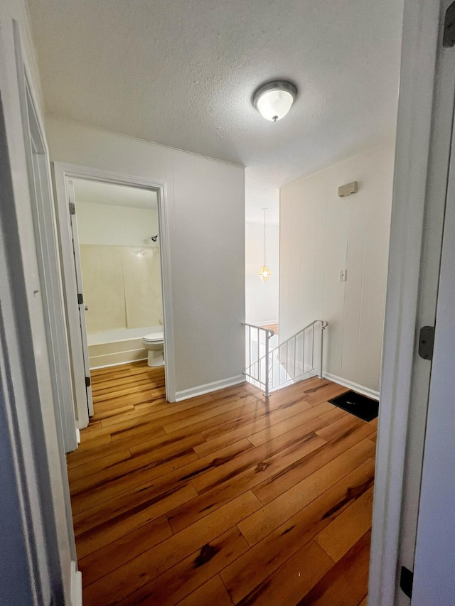 hall with wood-type flooring and a textured ceiling