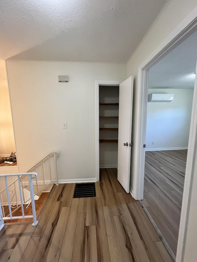 interior space featuring wood-type flooring, a textured ceiling, and a wall mounted AC