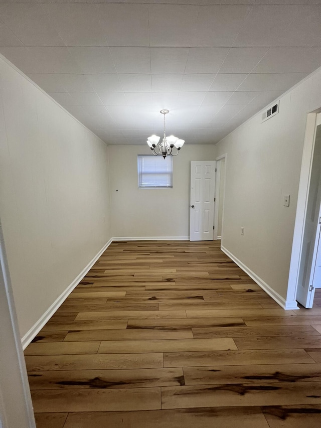 unfurnished dining area with hardwood / wood-style flooring and a notable chandelier