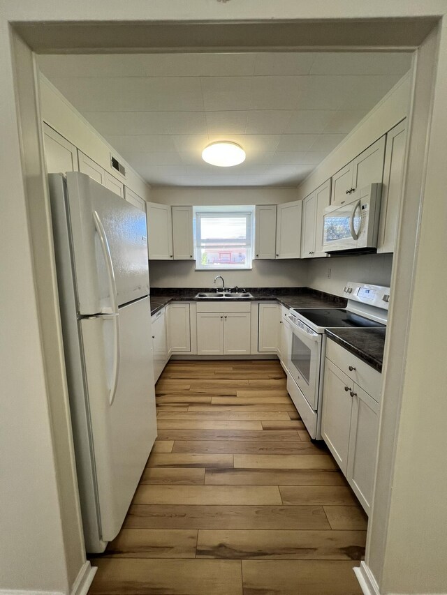 kitchen with sink, white cabinets, white appliances, and light wood-type flooring