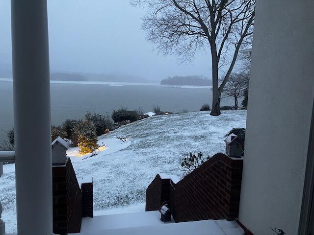yard covered in snow featuring a water view