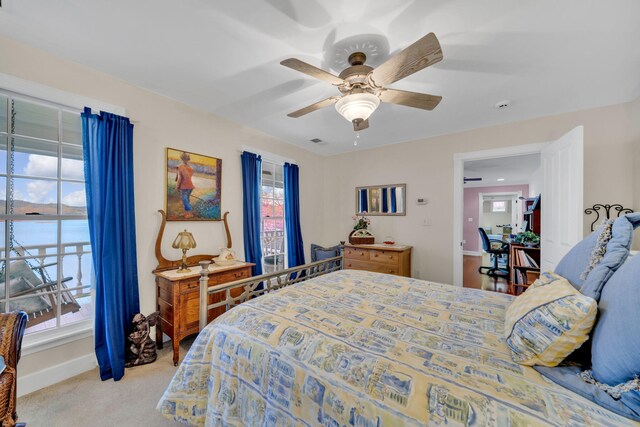 bedroom with light carpet, baseboards, a water view, and a ceiling fan