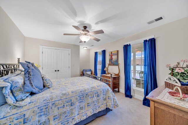 bedroom featuring light colored carpet, baseboards, ceiling fan, visible vents, and a closet