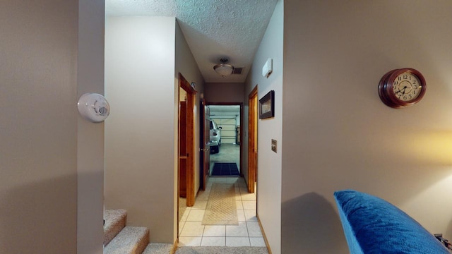 hall featuring light tile patterned floors and a textured ceiling