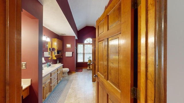 bathroom featuring vanity, toilet, and vaulted ceiling