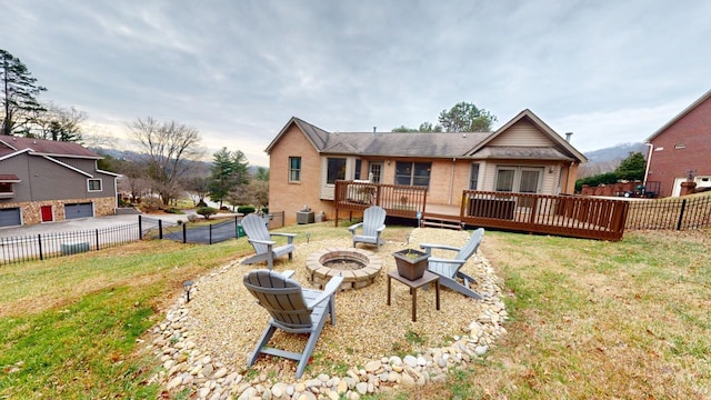 rear view of property featuring a deck with mountain view, a yard, and a fire pit