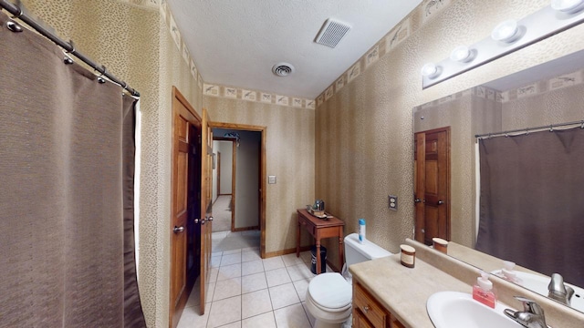 bathroom with tile patterned floors, vanity, a textured ceiling, and toilet