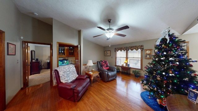 living room with wood-type flooring, a textured ceiling, ceiling fan, and lofted ceiling