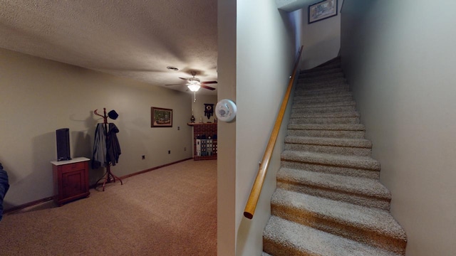 staircase with a textured ceiling, carpet floors, and ceiling fan