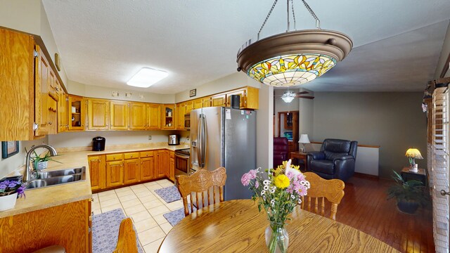 kitchen with sink, light tile patterned floors, a textured ceiling, and appliances with stainless steel finishes