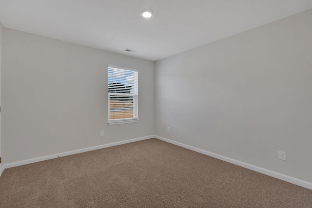 carpeted spare room featuring visible vents and baseboards