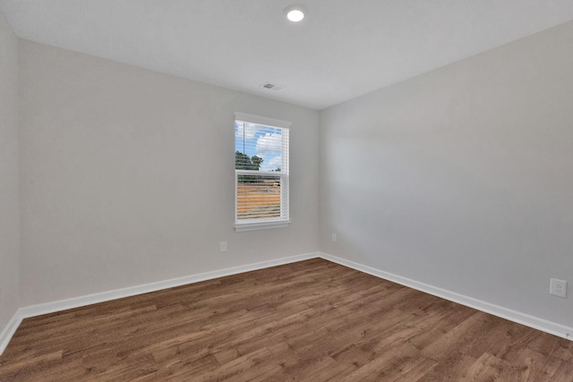 unfurnished room featuring dark wood-type flooring, visible vents, and baseboards