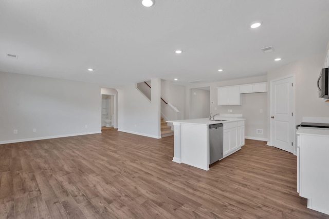 kitchen featuring stainless steel appliances, open floor plan, white cabinets, and a sink