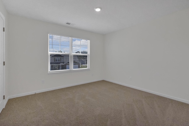 unfurnished room featuring carpet floors, visible vents, and baseboards