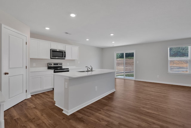 kitchen with appliances with stainless steel finishes, a sink, dark wood finished floors, and white cabinets