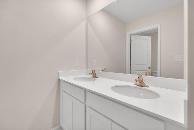 bathroom featuring baseboards, a sink, toilet, and double vanity