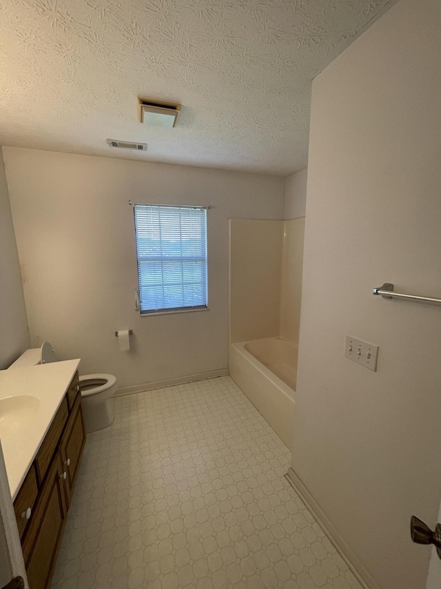 bathroom with toilet, vanity, tile patterned floors, a textured ceiling, and baseboards