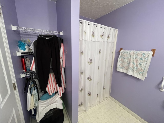 bathroom featuring baseboards, a shower with shower curtain, and a textured ceiling