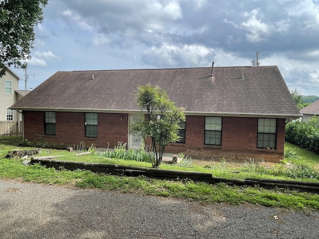 back of house featuring brick siding and roof with shingles