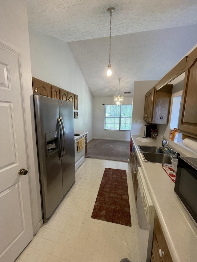 kitchen with white appliances, a textured ceiling, lofted ceiling, a sink, and a chandelier
