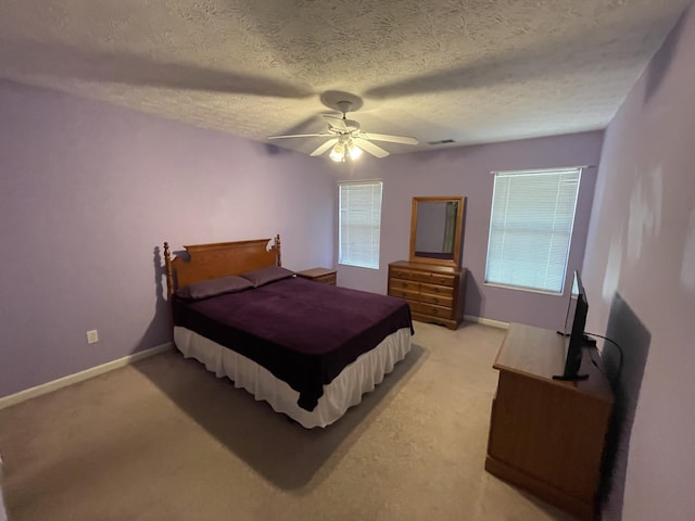 bedroom featuring light carpet, a ceiling fan, a textured ceiling, and baseboards