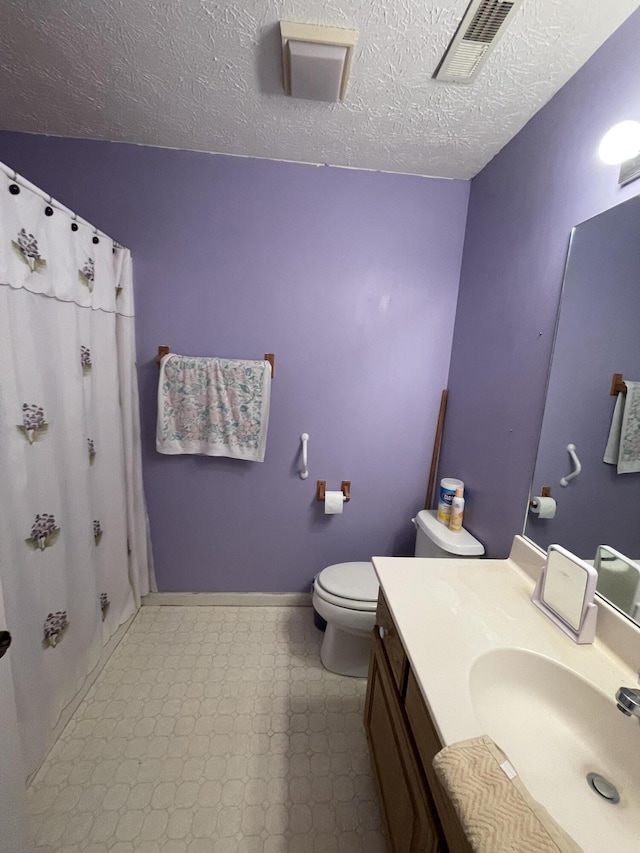 bathroom featuring tile patterned floors, toilet, vanity, a textured ceiling, and a shower with curtain