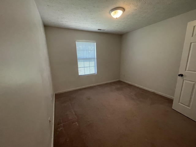 carpeted spare room with a textured ceiling and baseboards