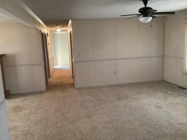 carpeted spare room featuring crown molding and ceiling fan