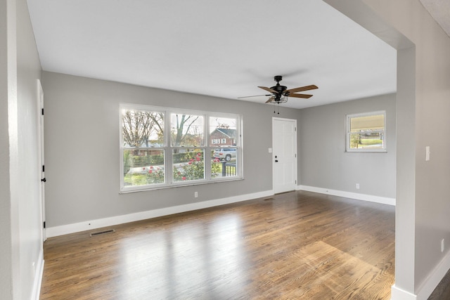 empty room featuring a healthy amount of sunlight, hardwood / wood-style floors, and ceiling fan