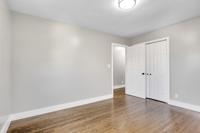 unfurnished bedroom with dark wood-type flooring and a closet