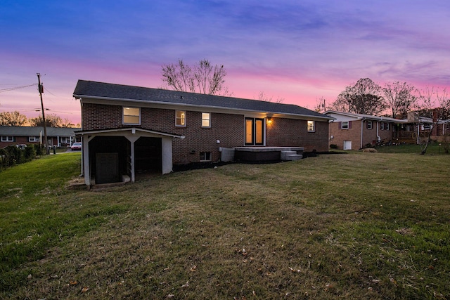 back house at dusk featuring central AC and a lawn