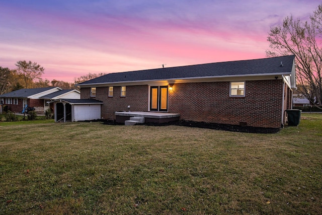 back house at dusk featuring a lawn