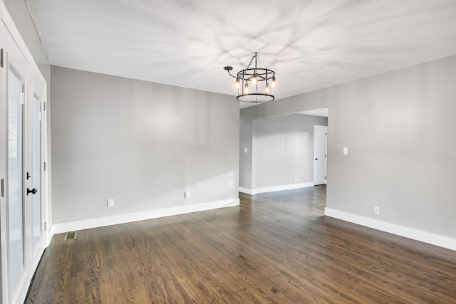 unfurnished room featuring dark hardwood / wood-style floors and a notable chandelier