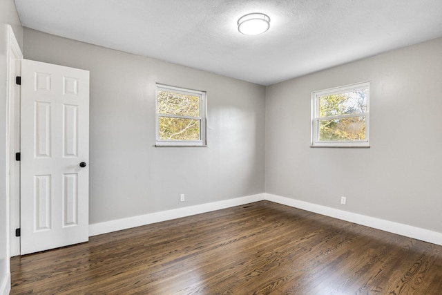 empty room featuring dark wood-type flooring and a wealth of natural light