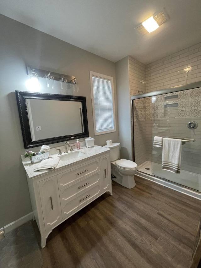 full bath with vanity, wood finished floors, baseboards, a shower stall, and toilet