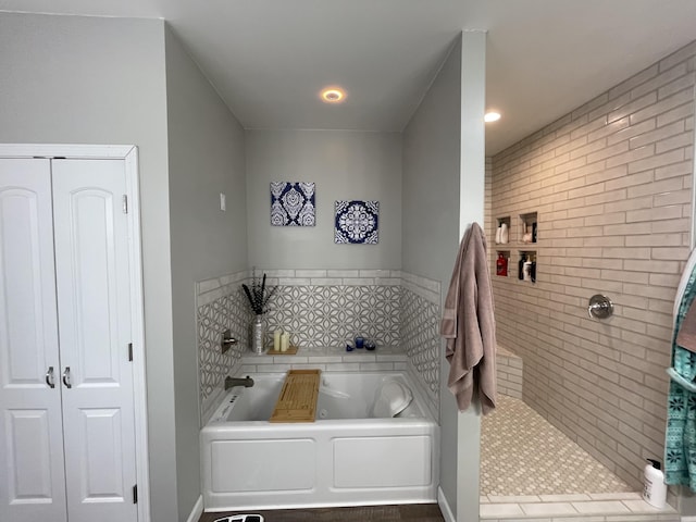 bathroom featuring a closet, a bath, and a tile shower