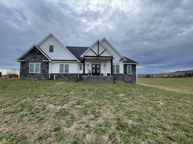 view of front facade with french doors, stone siding, and a front yard