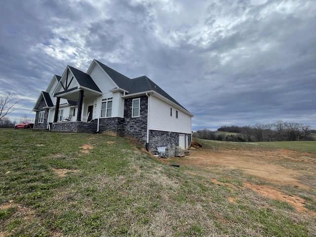 view of side of home featuring a garage, stone siding, and a lawn