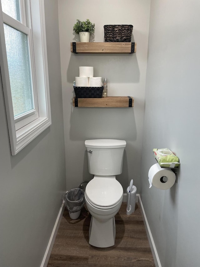 bathroom with a wealth of natural light, toilet, baseboards, and wood finished floors