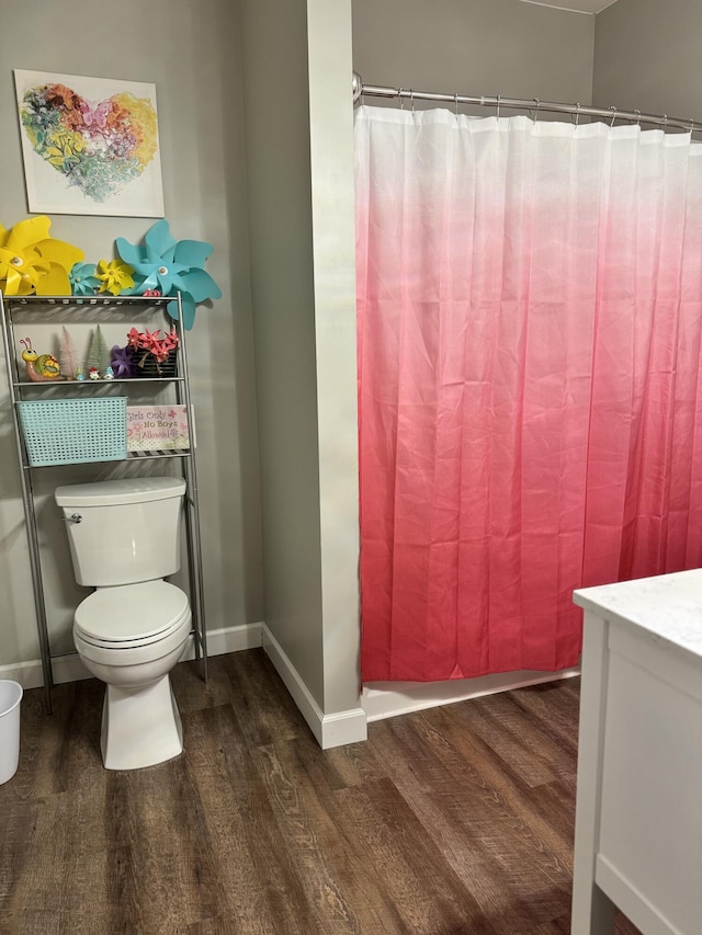 bathroom with a shower with shower curtain, baseboards, toilet, and wood finished floors