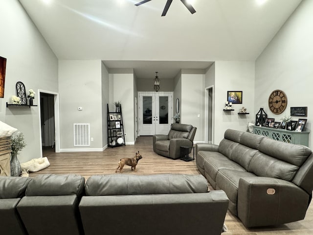 living area featuring visible vents, high vaulted ceiling, a ceiling fan, wood finished floors, and baseboards