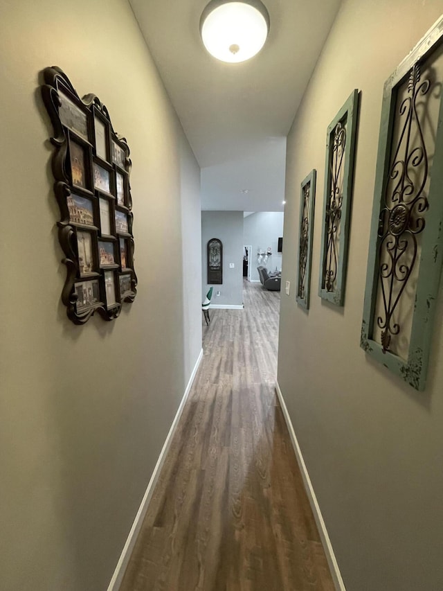 corridor featuring baseboards and wood finished floors