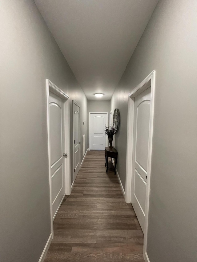 corridor featuring dark wood-style floors and baseboards