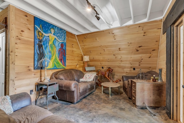 sitting room featuring concrete flooring, beamed ceiling, and wood walls