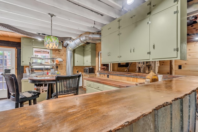 kitchen with decorative light fixtures, green cabinetry, and wood walls