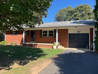 single story home featuring a garage, aphalt driveway, and a front yard