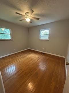 empty room with wood-type flooring, a ceiling fan, and baseboards