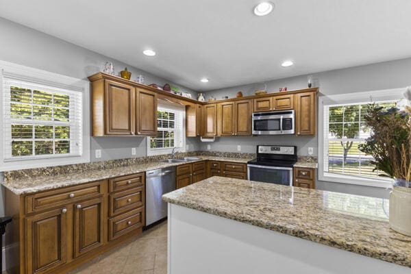 1211 W 6th N St, Morristown, TN 37814 - kitchen with appliances with stainless steel finishes, light stone countertops, brown cabinets, light tile patterned flooring, and recessed lighting