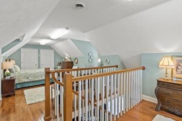 bedroom with lofted ceiling, visible vents, and wood finished floors